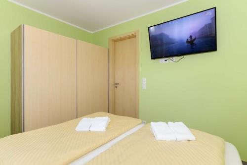 a bedroom with two beds and a flat screen tv on the wall at Residenz Waterkant in Bensersiel