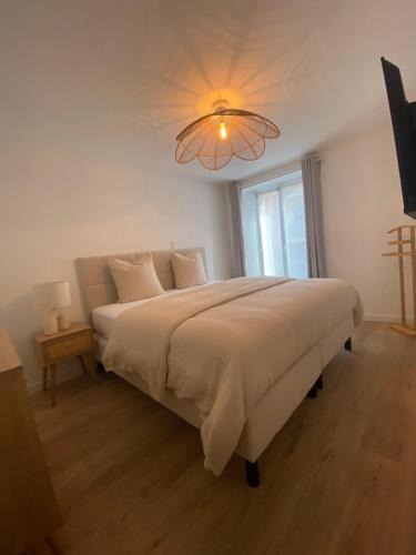 - une chambre avec un grand lit et un lustre dans l'établissement Duplex la parenthèse bretonne, à Auray
