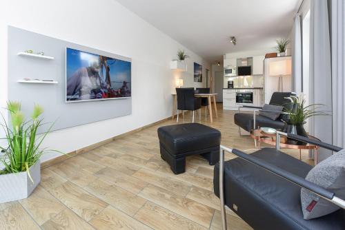 a living room with a couch and a tv on a wall at Residenz Waterkant in Bensersiel