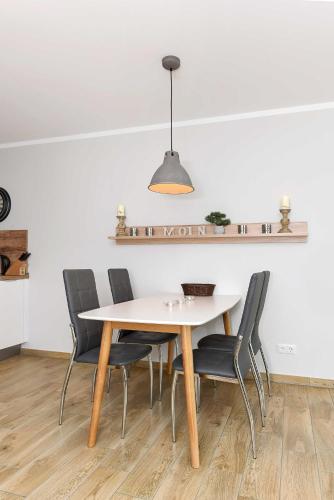 a dining room table with chairs and a light fixture at Residenz Waterkant in Bensersiel