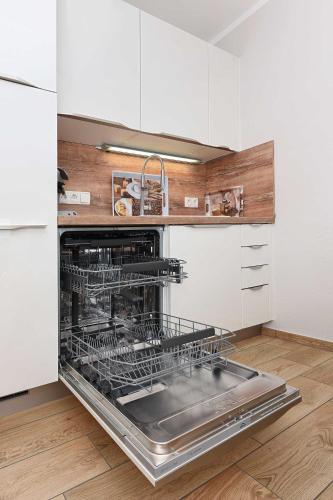 an open dishwasher in a kitchen with white cabinets at Residenz Waterkant in Bensersiel