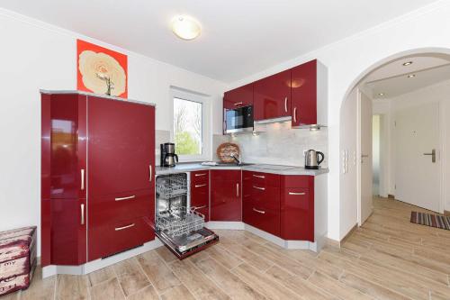 a large kitchen with red cabinets and a counter at Residenz Waterkant in Bensersiel