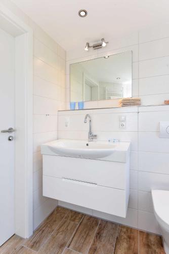 a white bathroom with a sink and a mirror at Residenz Waterkant in Bensersiel
