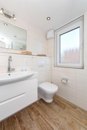 a bathroom with a toilet and a sink and a window at Residenz Waterkant in Bensersiel