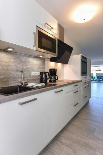 a white kitchen with a sink and a microwave at Residenz Waterkant in Bensersiel