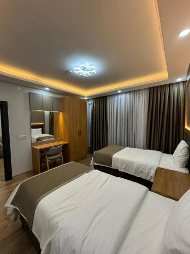 Habitación de hotel con 2 camas y escritorio en Gürtürkler Suit Otel, en Muş