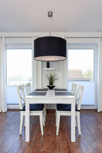 a white dining room table with chairs and a potted plant at Residenz Waterkant in Bensersiel