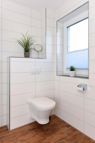 a white bathroom with a toilet and a window at Residenz Waterkant in Bensersiel