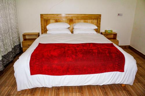 sypialnia z dużym łóżkiem i czerwonym kocem w obiekcie The Little Home w mieście Arusza