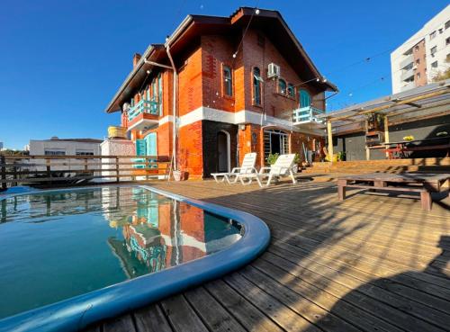 a building with a swimming pool on a deck at Casa do Rogério Hostel in Caxias do Sul