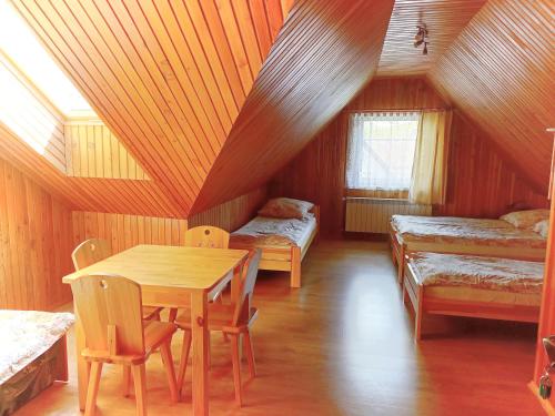 a room with a table and two beds in a attic at Spiska Sadyba in Łapsze Niżne