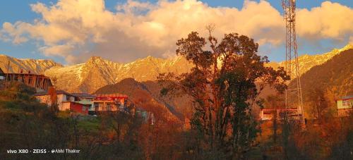 a view of a mountain range with a tree in the foreground at Abhi house in McLeod Ganj