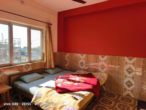 a bed in a room with a red wall at Abhi house in McLeod Ganj