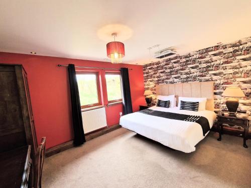 a bedroom with a bed and a red wall at Lbtie Lodge with Two Private Hot Tubs - Fife - Loch Leven - Lomond Hills in Kelty