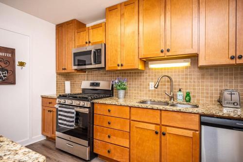 a kitchen with wooden cabinets and a stove and a sink at Downtown! 5 Beds! Onsite Parking! City View! New Renovated! LM1806 in Atlanta