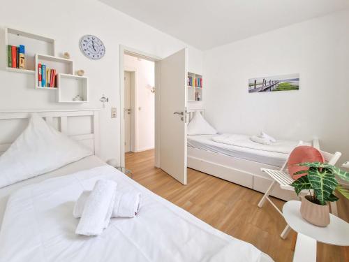 a white bedroom with a bed and a mirror at Kleine Krabbe in Greetsiel