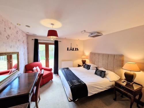 a bedroom with a large bed and a red chair at Lbtie Lodge with Two Private Hot Tubs - Fife - Loch Leven - Lomond Hills in Kelty