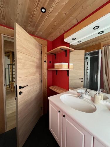 La salle de bains est pourvue de 2 lavabos et d'un mur rouge. dans l'établissement Le Balcon de Bramont, à La Bresse