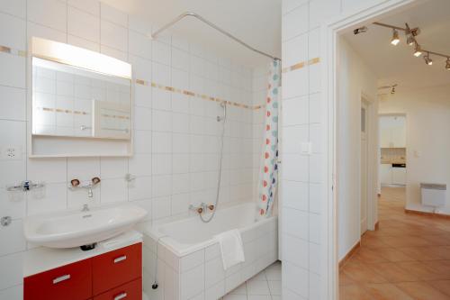 ein weißes Badezimmer mit einer Badewanne und einem Waschbecken in der Unterkunft Brissago Lake Apartment in Brissago
