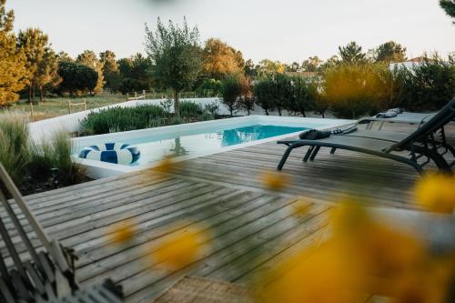 a swimming pool with a wooden deck and a bench at Casa 7 boxes - amazing villa with heated pool in Comporta