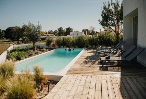 a swimming pool with a wooden deck and benches at Casa 7 boxes - amazing villa with heated pool in Comporta