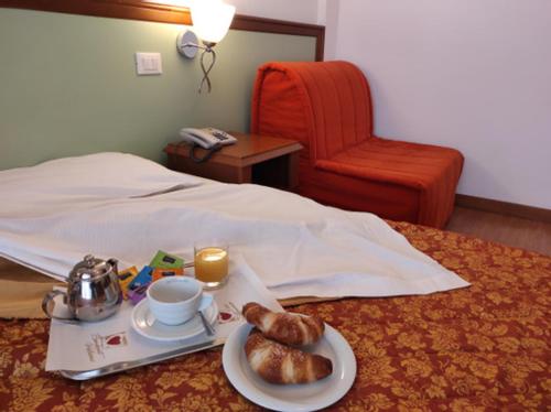 a breakfast tray with a plate of food on a bed at Hotel Il Guscio in Grado