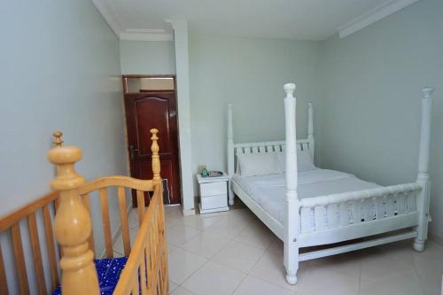 a bedroom with two white beds and a staircase at Serene Lakeside Home in Entebbe