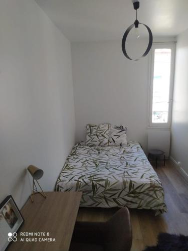 Schlafzimmer mit einem Bett und einem Holztisch in der Unterkunft A proximité des JO! in Aubervilliers