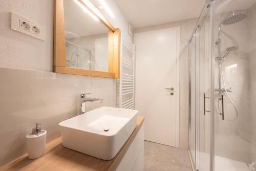 a white bathroom with a sink and a shower at Apartments BB in Bohinj