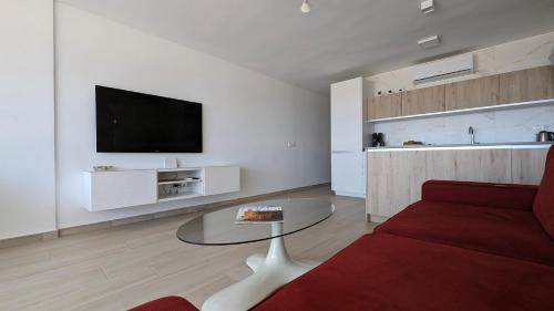 ESMERALDA sea front apartment في بنيدورم: غرفة معيشة مع أريكة حمراء وطاولة زجاجية