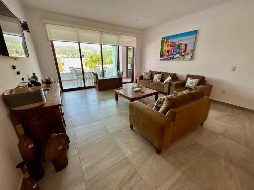 a living room with two couches and a table at El Tular 2 Bdr Appartment 2 min walk from La Ropa beach in Zihuatanejo