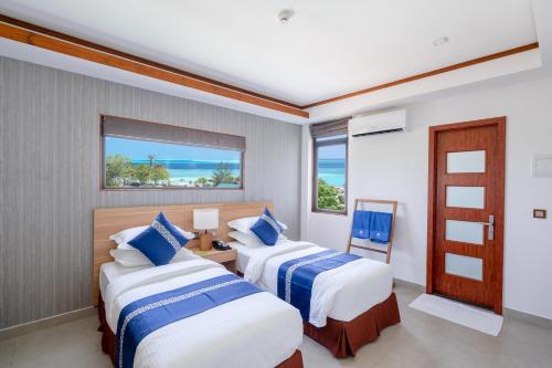 two beds in a room with a view of the ocean at Ayala Oceanview Maldives in Gulhi