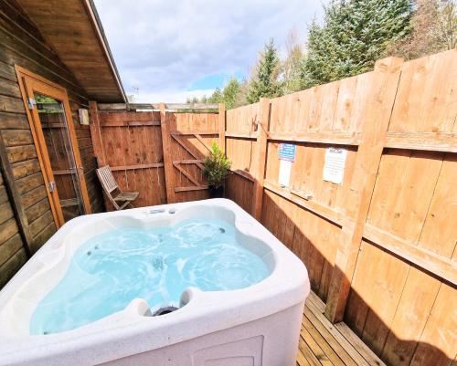 bañera de hidromasaje en una terraza con una valla de madera en Lomond 3 with Private Hot Tub - Fife - Loch Leven - Lomond Hills -Pet Friendly, en Kelty
