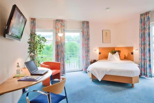 a hotel room with a bed and a desk with a laptop at Aspire Kronprinz, Trademark Collection by Wyndham in Schwäbisch Hall
