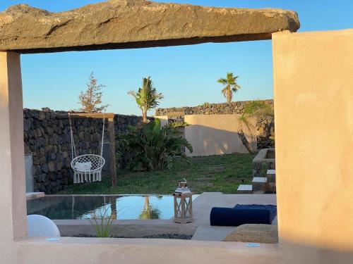 a view of a backyard with a swing and a pool at Dammuso Elisir Rosa - Jacuzzi e Giardino Privati in Pantelleria