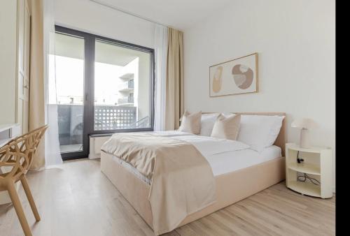 een witte slaapkamer met een bed en een groot raam bij Magnolie Suite Presidential Garden Free Parking in Bratislava