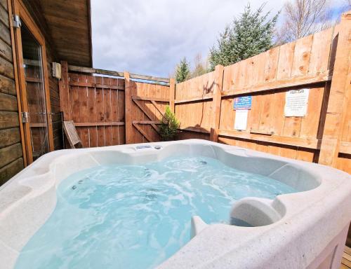 una bañera de hidromasaje en un patio trasero con una valla de madera en Lomond 2 with Private Hot Tub - Fife - Loch Leven - Lomond Hills en Kelty