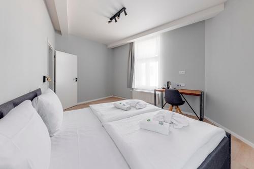 a white bedroom with two beds and a desk at Koruna Hotel in Prague