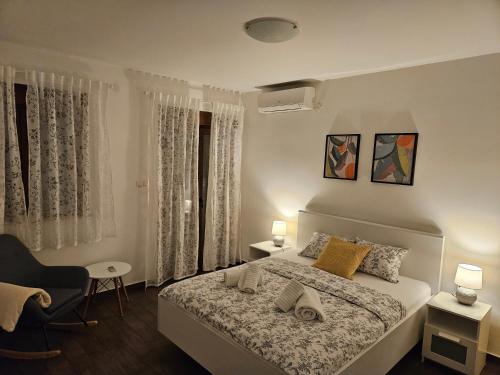 ein weißes Schlafzimmer mit einem Bett und einem Stuhl in der Unterkunft Kristy's Place in Crikvenica