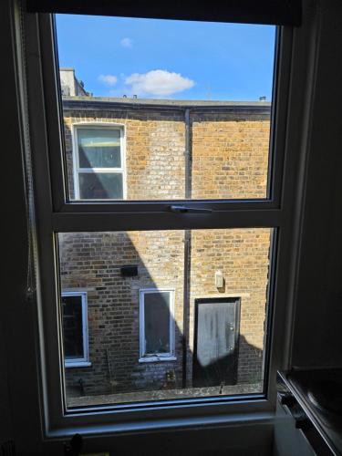 a window with a view of a brick building at Tiny Studio, 30 min to St. Pancras, North London in London