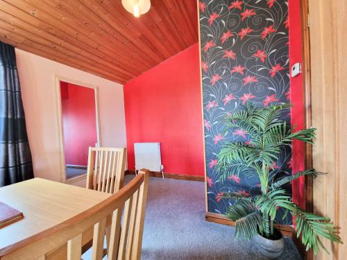 a dining room with a table and a red wall at Lomond 4 with Private Hot Tub - Fife - Loch Leven - Lomond Hills in Kelty