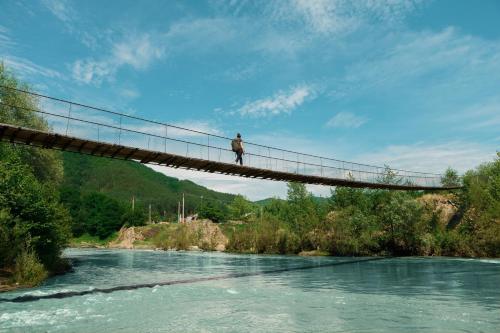 eine Person, die auf einer Hängebrücke über einen Fluss steht in der Unterkunft Pensiunea Valea Lupului in Valea Lupului