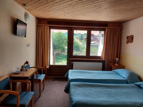 a room with two beds and a table and a window at Pensiunea Valea Lupului in Valea Lupului