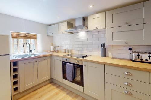 a kitchen with white cabinets and a sink at The Tower Simonsbath in Simonsbath