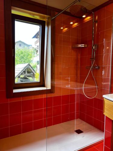 a red tiled bathroom with a shower with a window at B&B Il Tabià in Pieve di Cadore