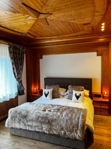a bedroom with a large bed with a wooden ceiling at B&B Il Tabià in Pieve di Cadore