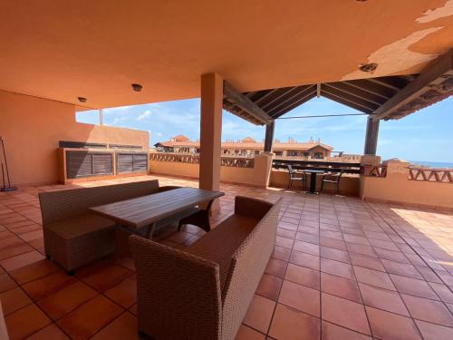 patio con mesa de madera y sillas en el balcón en Apartamentos Turísticos Spiritmar, en Almerimar