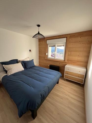 - une chambre avec un grand lit bleu et une fenêtre dans l'établissement Le Balcon de Bramont, à La Bresse