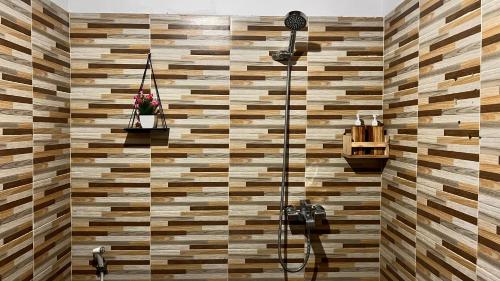 uma casa de banho com um chuveiro e uma parede de madeira em Dewangga Mountain View em Bangli
