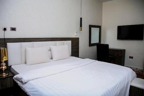 1 dormitorio con 1 cama blanca y 2 almohadas en MO-House Hotels and Apartments Mabushi, en Abuja
